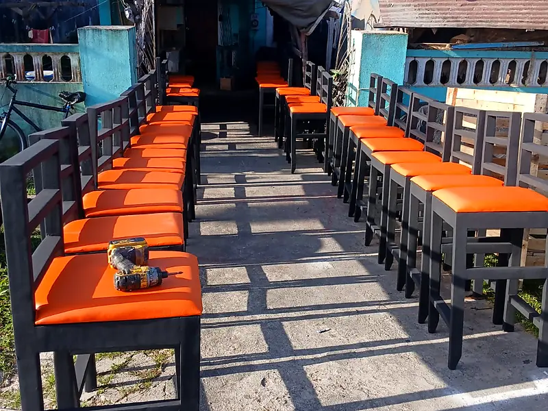 Two long rows of black bar chairs with orange seats ready for delivery