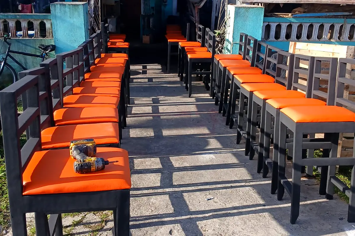 Two long rows of new bar chairs with orange seats ready for a restaurant