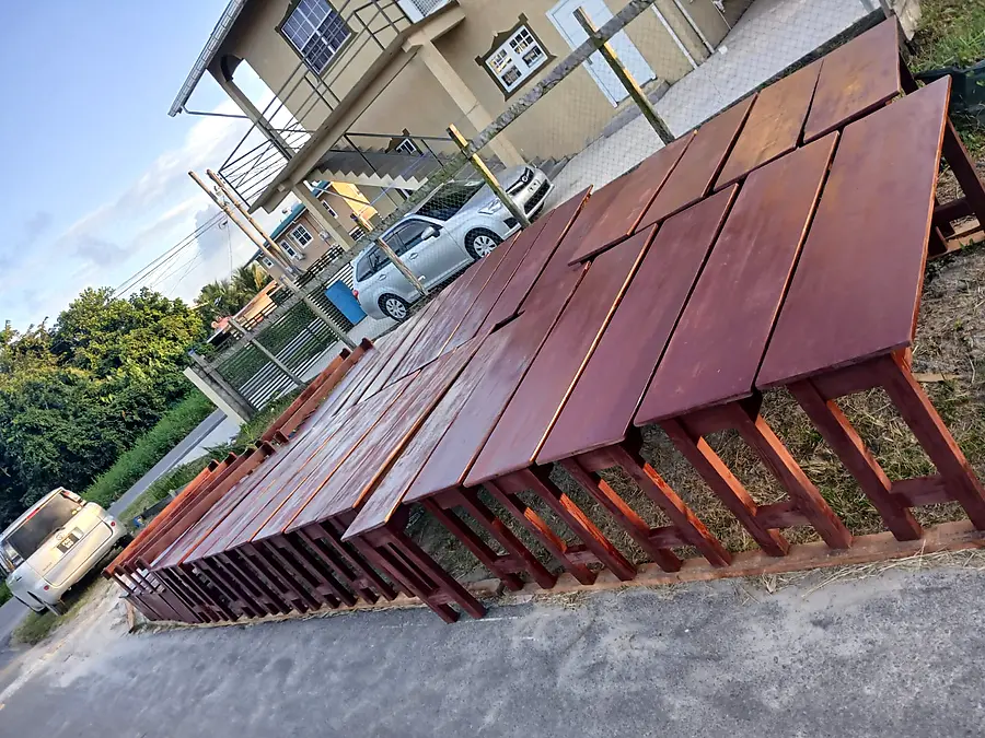Many new dark-stained restaurant tables drying in the sun